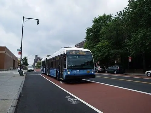 A bus driving down the street on a cloudy day.