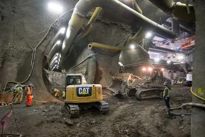 Bulldozer and excavator operators coordinate excavation operations inside the cross-cut cavern, where left side drift invert work for the south platform cavern has begun. (Bulldozer and excavator operators coordinate excavation operations inside the c